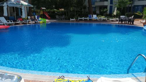 a large blue swimming pool with chairs and tables at Excelsior Prince ApartHotel in Sunny Beach