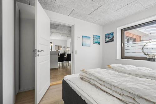 een witte slaapkamer met een bed en een spiegel bij 8811-Hvide-Sande-Vesterhavsvej-3-stuen in Hvide Sande