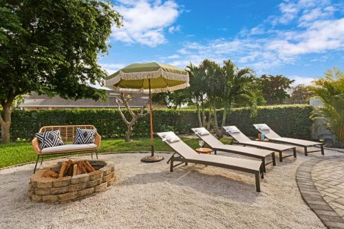 a group of chairs and an umbrella next to a fire pit at colorfully designed 4 bedroom home with pool in Pompano Beach