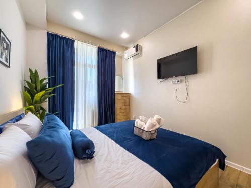 a bedroom with a bed with blue pillows and a flat screen tv at Monroe Chic Studio in Tbilisi City
