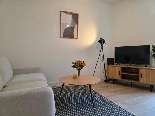 a living room with a couch and a table with a tv at T2 Cosy Centre ville Clim & Wifi in Aubenas