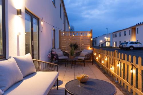 a balcony with a couch and a table with lights at Modern Ground Floor Corner Flat with Rustic Patio in Båstad