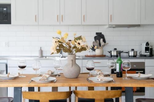 a kitchen table with a vase of flowers and wine glasses at Modern Ground Floor Corner Flat with Rustic Patio in Båstad