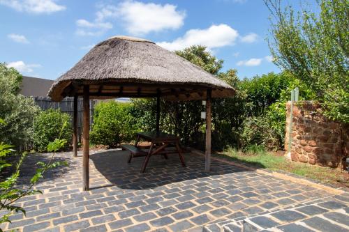 a picnic table and a straw umbrella with a bench at Nullarbor Cottages in Magaliesburg