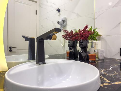 a bathroom sink with a faucet and flowers on a counter at Monroe Chic Studio in Tbilisi City