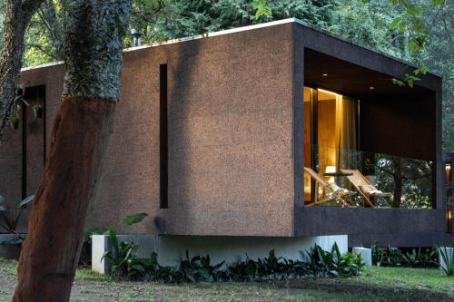a brick house with a large window next to a tree at Nature Escape with Pool & BBQ in Viana do Castelo