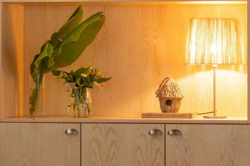 a table with a vase of flowers and a lamp at Nature Escape with Pool & BBQ in Viana do Castelo