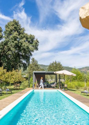a woman is standing next to a swimming pool at Nature Escape with Pool & BBQ in Viana do Castelo