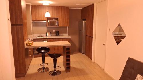 a small kitchen with a counter and stools in it at Condominio en el Centro de Calama in Calama