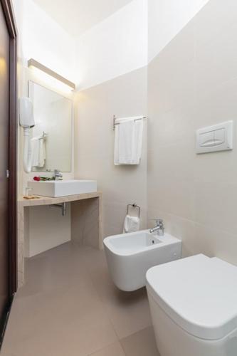 a white bathroom with a toilet and a sink at Hotel President in Alba Adriatica