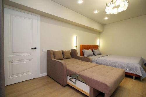 a bedroom with a couch and a bed and a door at Center Almaty in Almaty