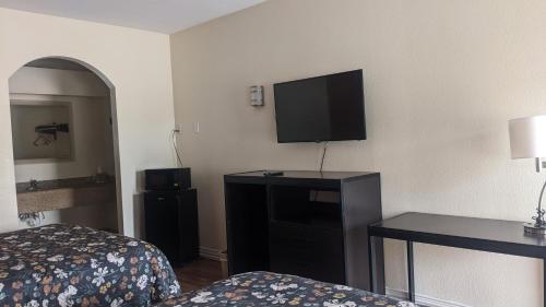 a hotel room with a bed and a flat screen tv at Rodeway Inn & Suites in Humble
