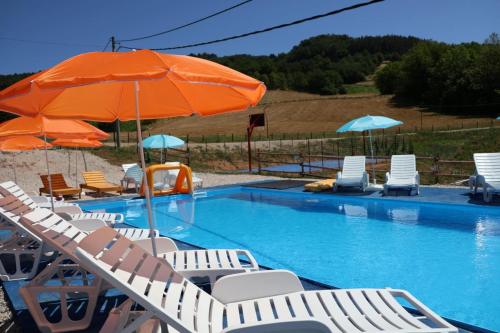 Una piscina con tumbonas y una sombrilla naranja. en Pavlovica konaci, en Kotraža
