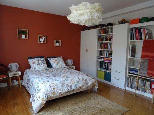 ein Schlafzimmer mit orangefarbenen Wänden, einem Bett und einem Kronleuchter in der Unterkunft Charmante chambre chez l'habitant pour 2 personnes- parking couvert in Le Mans