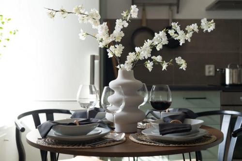 a table with a vase with flowers and glasses of wine at Fully Equipped Apartment Close to Malmö & Copenhagen in Vellinge