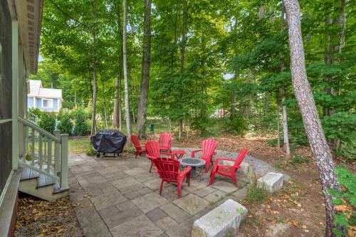a patio with red chairs and tables in the woods at The Jack Pine - 50 Hollow in Cherry Valley