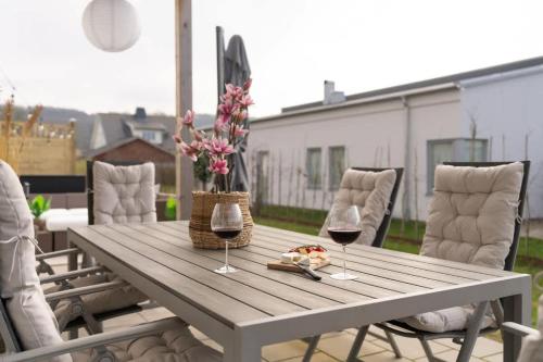 a wooden table with two glasses of wine and flowers at Fully Equipped Home in Båstad with Cozy Patio in Båstad