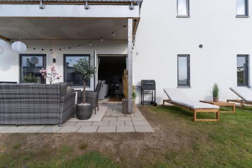 a patio of a house with a couch and a table at Earthy Ground Floor Home with Patio Sunbeds Greenery in Båstad