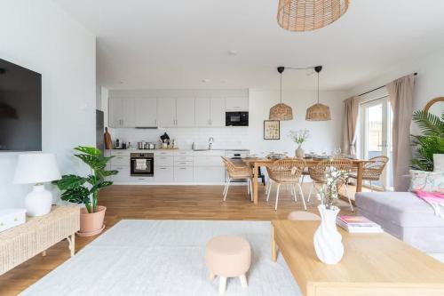 a living room with a table and a kitchen at Bright Ground Floor Corner Home with Cozy Outdoor in Båstad