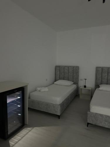 Un dormitorio con dos camas y un televisor de pantalla plana. en Gold Rooms II, en Sarandë