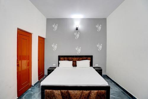 a bedroom with a bed and a red door at Hotel O Conifer INN in Meerut