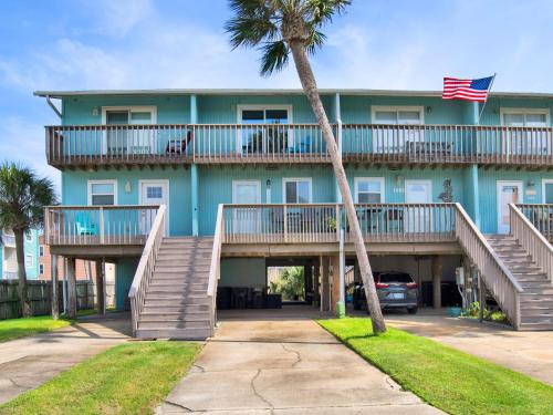a large blue building with stairs and a palm tree at Coconuts Beach House in Pensacola Beach