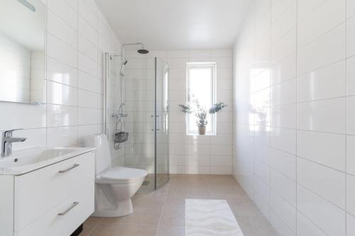 a white bathroom with a toilet and a shower at Chocolaty Warmth Home 3BR Flat with Cozy Balcony in Båstad