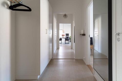 a hallway with white walls and a mirror at Chocolaty Warmth Home 3BR Flat with Cozy Balcony in Båstad