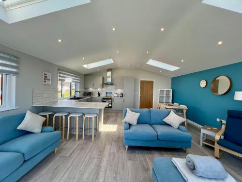 sala de estar con 2 sofás azules y cocina en Seaside Getaway with Balcony & Ocean Views - Westward Ho!, en Westward Ho