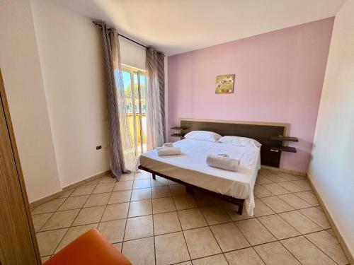 a bedroom with a bed with pink walls and a window at Conca Degli Dei in Paestum