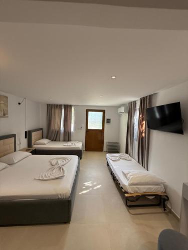 una camera da letto con due letti e una televisione di Green cottage a Ksamil