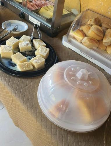 a table with a plate of food and a tray of bread at Pousada Bons Ventos in Paraty