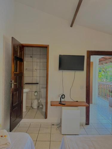 a room with a bathroom with a tv on the wall at Pousada Bons Ventos in Paraty