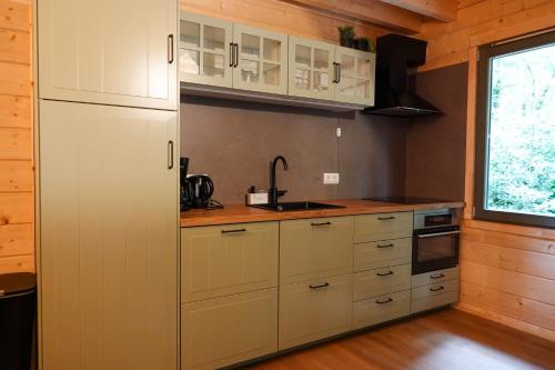 a kitchen with white cabinets and a sink and a window at Jesse's Log Cabin in Norg