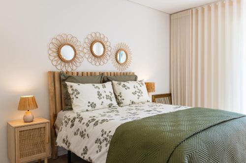 a bedroom with a bed and two mirrors on the wall at Aurora do Furadouro in Ovar