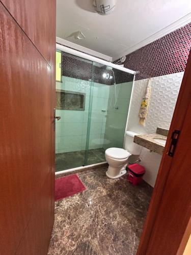 een badkamer met een glazen douche en een toilet bij Apê Dunas do Forte in Cabo Frio
