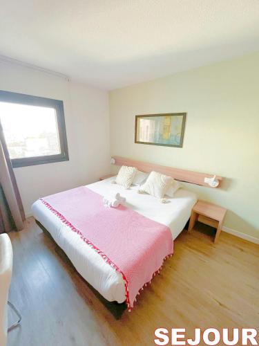 une chambre avec un grand lit avec une couverture rose dans l'établissement 5 minutes du Parc de la Villette - Charmant studio, à Pantin