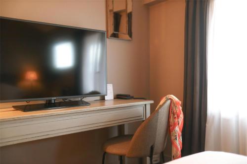 a flat screen tv sitting on top of a fireplace at Best Western Plus d'Europe et d'Angleterre in Mâcon