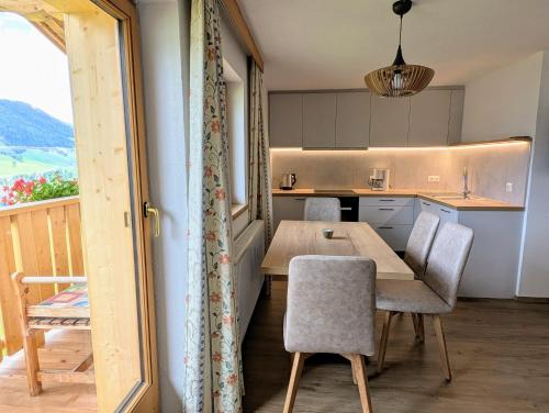 a kitchen with a table and chairs and a kitchen with a view at Neuhauserhof in Kartitsch