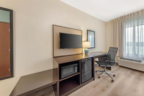 a room with a desk with a television and a chair at Sleep Inn & Suites Norman near University in Norman