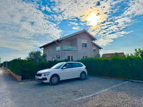 a white car parked in a parking lot in front of a house at Family Apartments Stefan in Budva