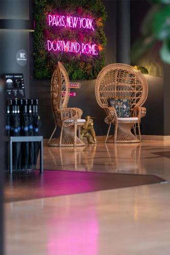 two wicker chairs and a table with wine bottles at Radisson Blu Hotel Dortmund in Dortmund