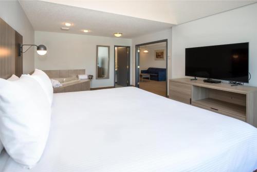 a bedroom with a large white bed and a flat screen tv at Coast Hinton Hotel in Hinton