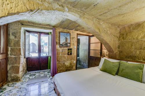 a bedroom with a bed in a stone wall at Serene Escape Farmhouse B&B in San Katald
