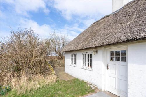 a white cottage with a thatched roof and a door at 315-Hvide-Sande-Holmsland-Klitvej-115-vest in Hvide Sande