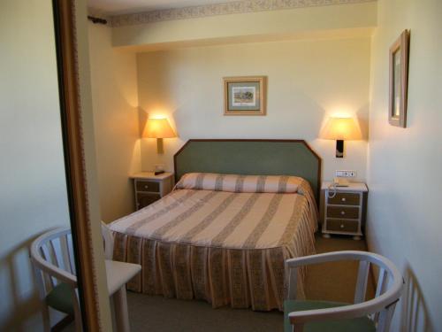 a hotel room with a bed and two tables and two lamps at Hotel Magallón in Caspe