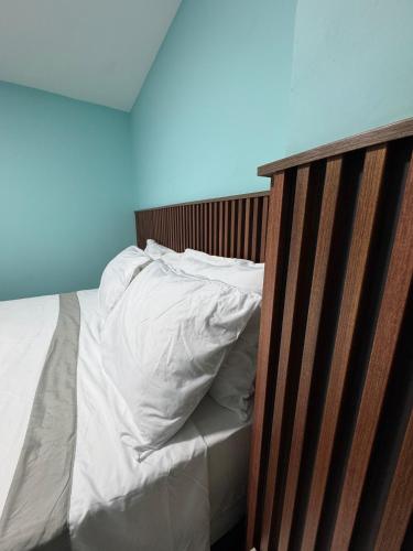 a bed with white sheets and a wooden headboard at Hostel43 in Estación El Salto