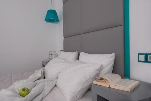 a bed with white pillows and a book on a table at Sweet Pop in Fira