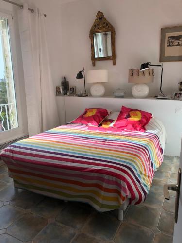 une chambre avec un grand lit avec une couverture colorée dans l'établissement Magnifique villa vue mer et piscine, à Bandol