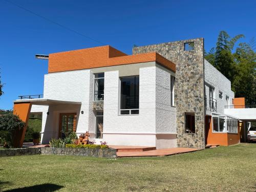 a white and orange house on a green lawn at Hotel Familiar El Remanso Del Agua in Guatapé